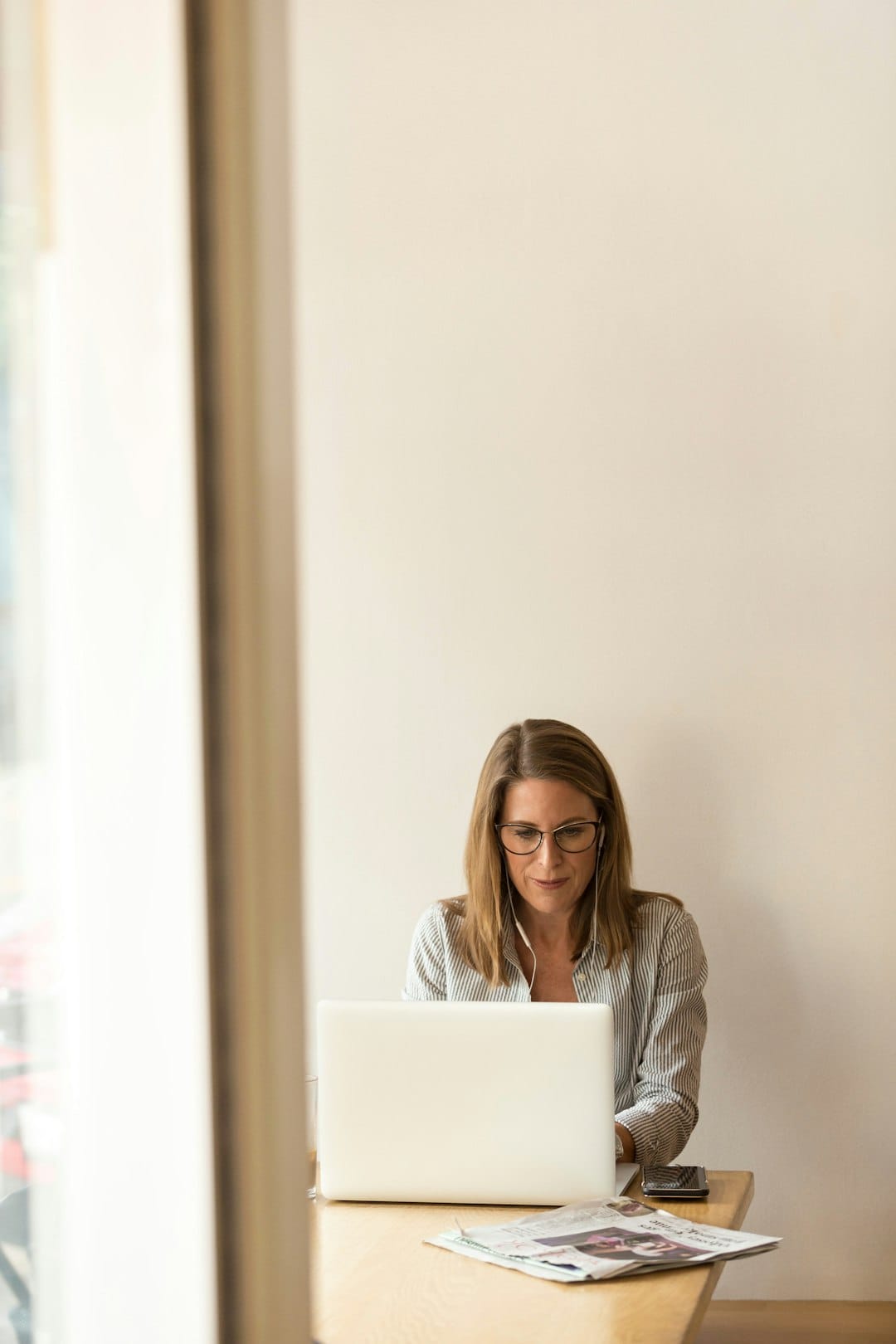 contact-img-01 woman-wearing-grey-striped-dress-shirt-sitting-down-near-brown-wooden-table-in-front-of-white-laptop-computer-ws73le0gnks