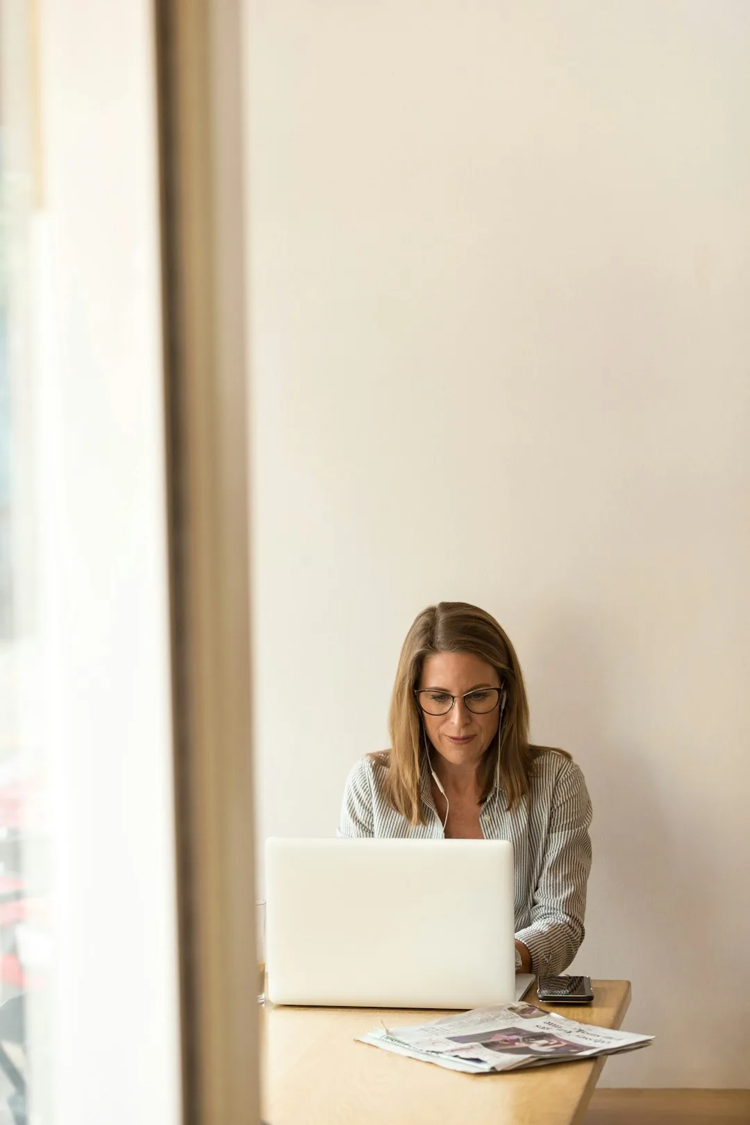 contact-img-01 woman-wearing-grey-striped-dress-shirt-sitting-down-near-brown-wooden-table-in-front-of-white-laptop-computer-ws73le0gnks